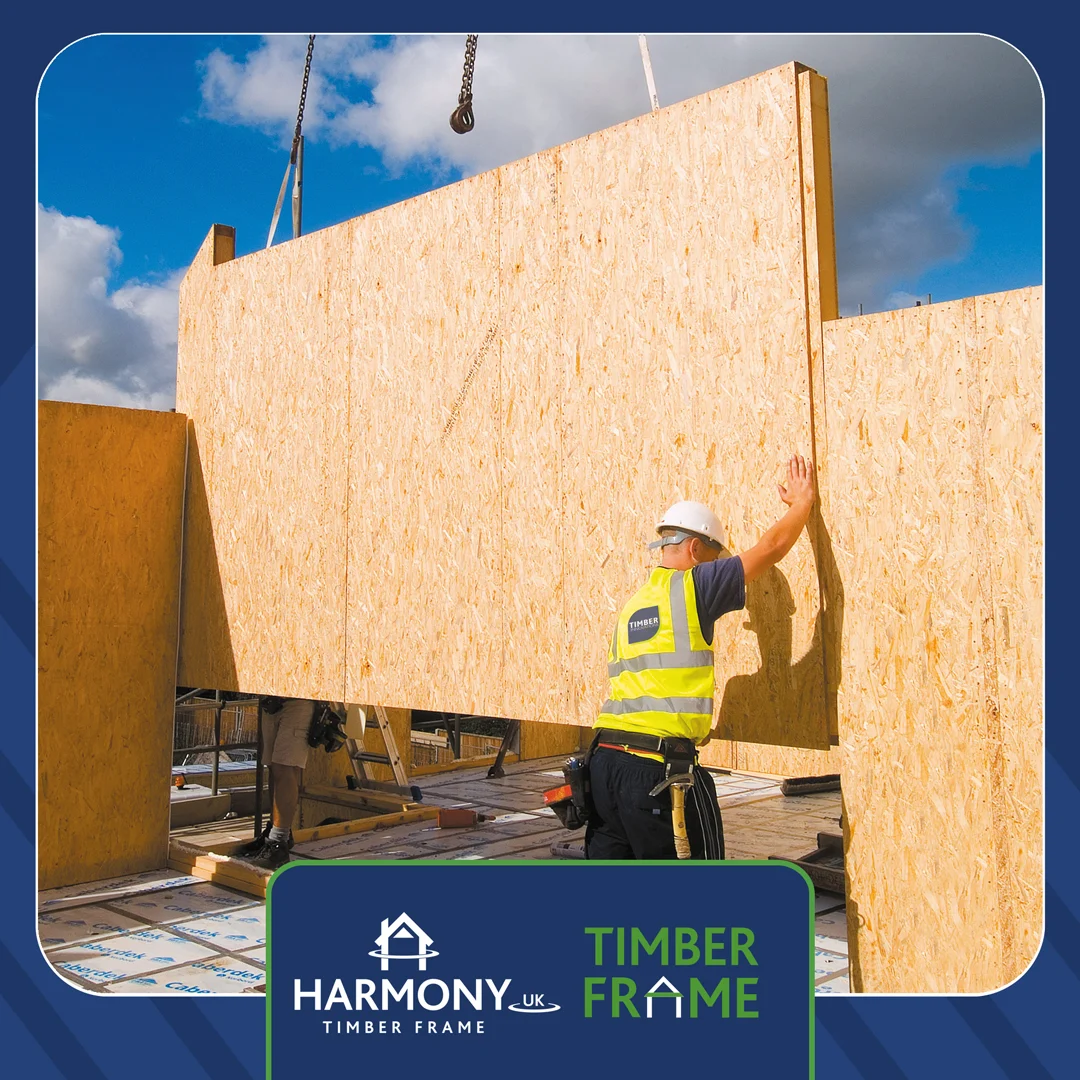 Man lowering a timber frame on building site.